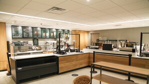 L’intérieur d’un café moderne, avec un comptoir, un espace salon et des panneaux d’affichage présentant le menu.