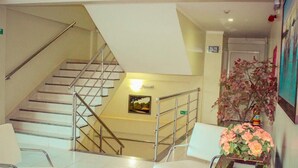 A hotel lobby with a staircase, a reception desk, and a floral arrangement. - Hotel Caribe (Porto Velho)