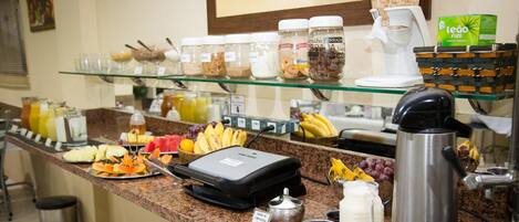 A buffet counter with various food items, condiments, and a coffee machine.