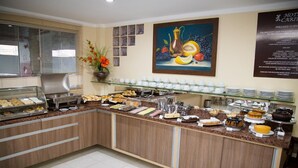 A buffet area with various food items, a coffee station, and a painting on the wall. - Hotel Caribe (Porto Velho)