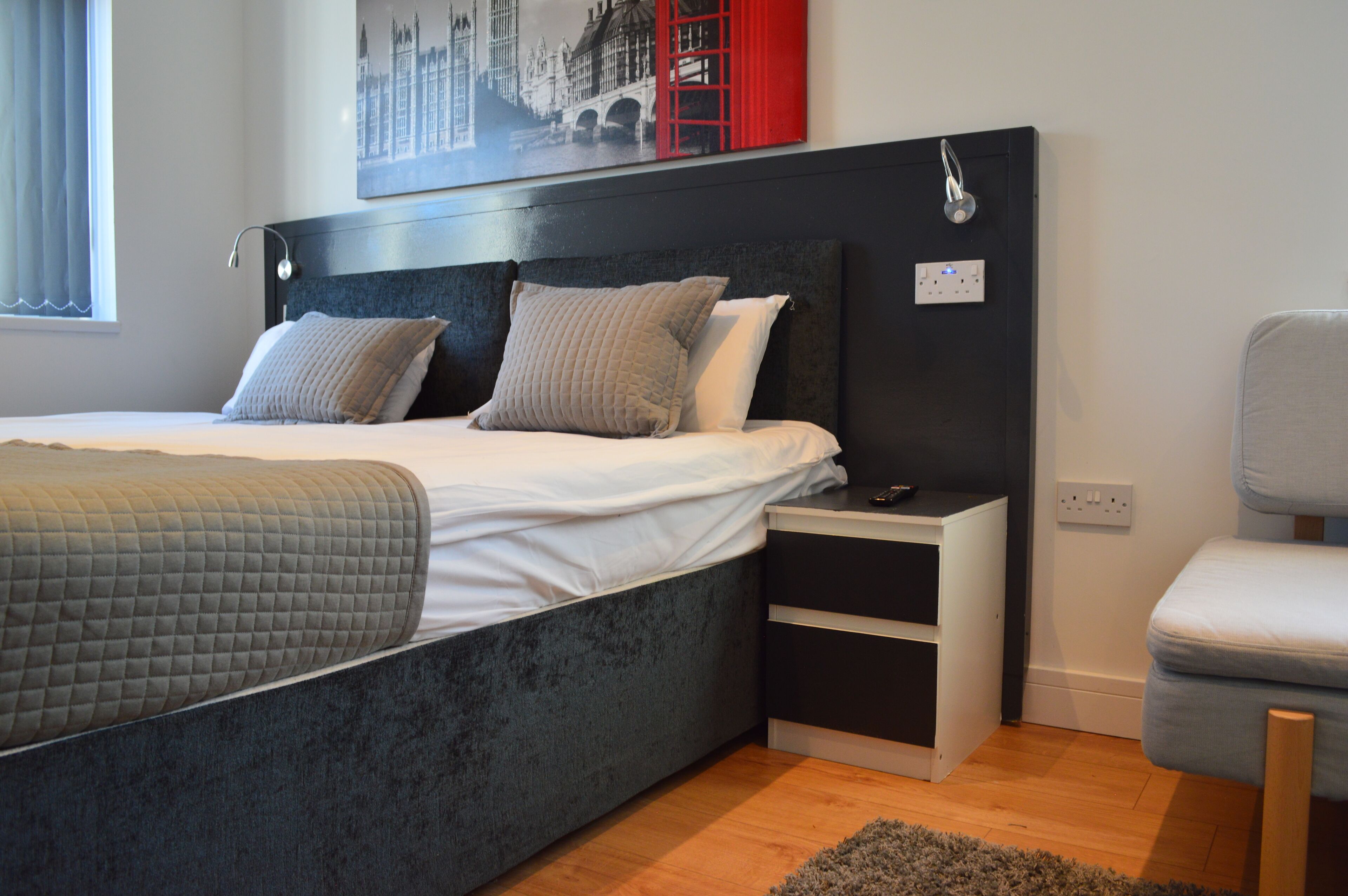 A modern bedroom with a bed, bedside tables, and a chair.