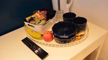 A tray with snacks, a banana, an apple, and a remote control on a table.