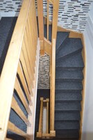 Una escalera de madera con peldaños alfombrados que bajan.