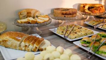 A buffet table with various food items including cakes, pastries, and sandwiches.