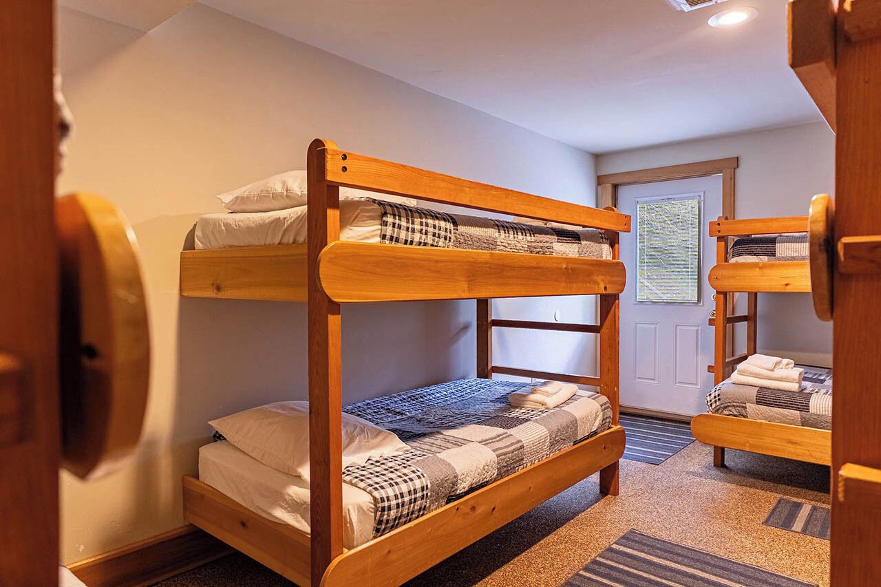 Een slaapkamer met stapelbed, een deur, een raam en een vloerbedekking.