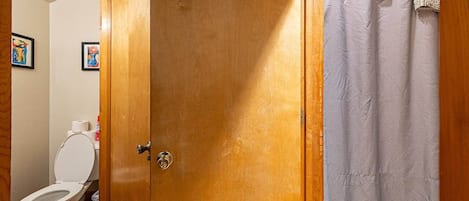 Puerta de madera que da a un baño con inodoro y cortina de ducha.