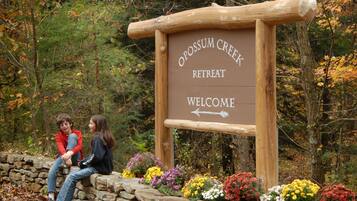 A wooden sign with the text "Opossum Creek Retreat Welcome" and a directional arrow.
