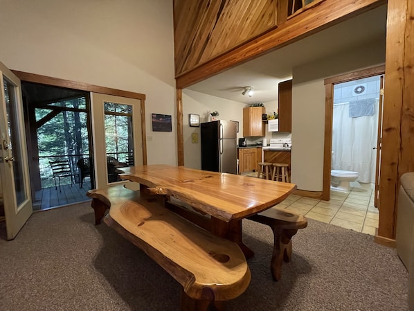 Una mesa de madera con bancos en una habitación con vistas a un bosque a través de un ventanal.