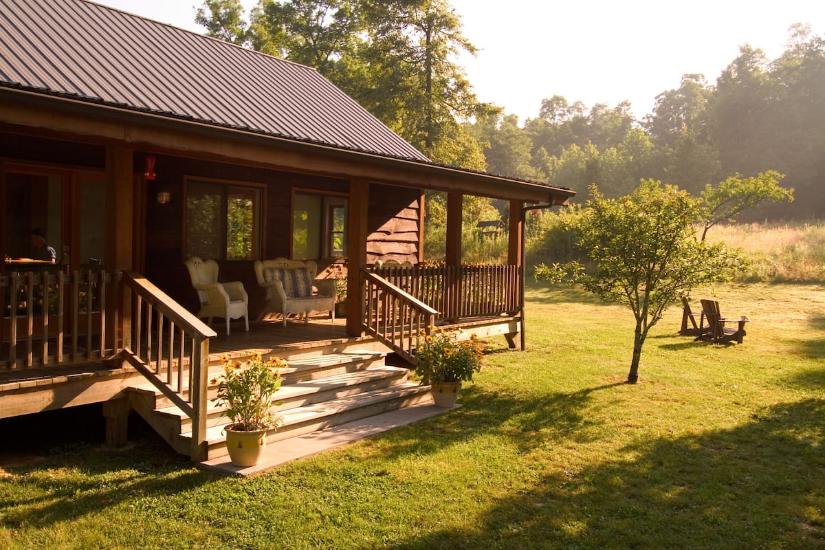 A wooden cabin with a porch, outdoor seating, and a small garden.