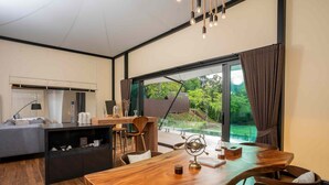 Una sala de estar moderna con una mesa de comedor de madera, un sofá y una zona de cocina con barra.