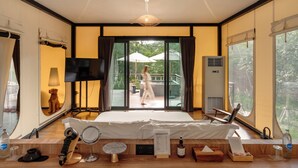 Un dormitorio amplio con una cama grande, un televisor, un espejo y una mesita de madera con artículos de tocador.