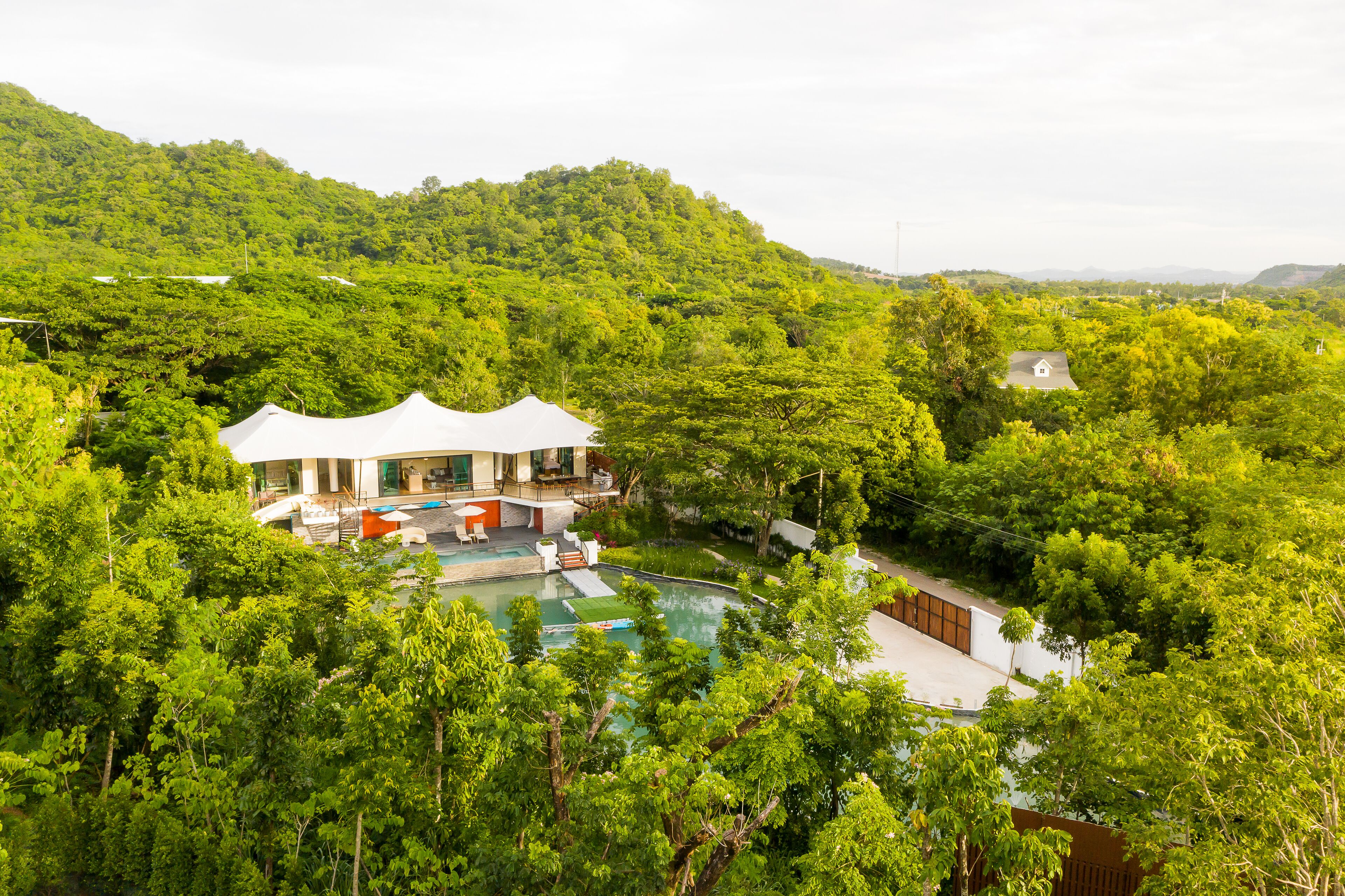 A house with a swimming pool surrounded by lush greenery and hills.