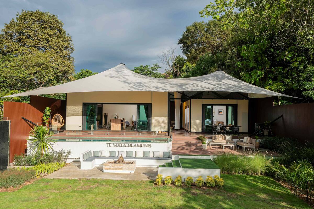 Una casa moderna con un amplio patio, una piscina y un espacio de estar cubierto.