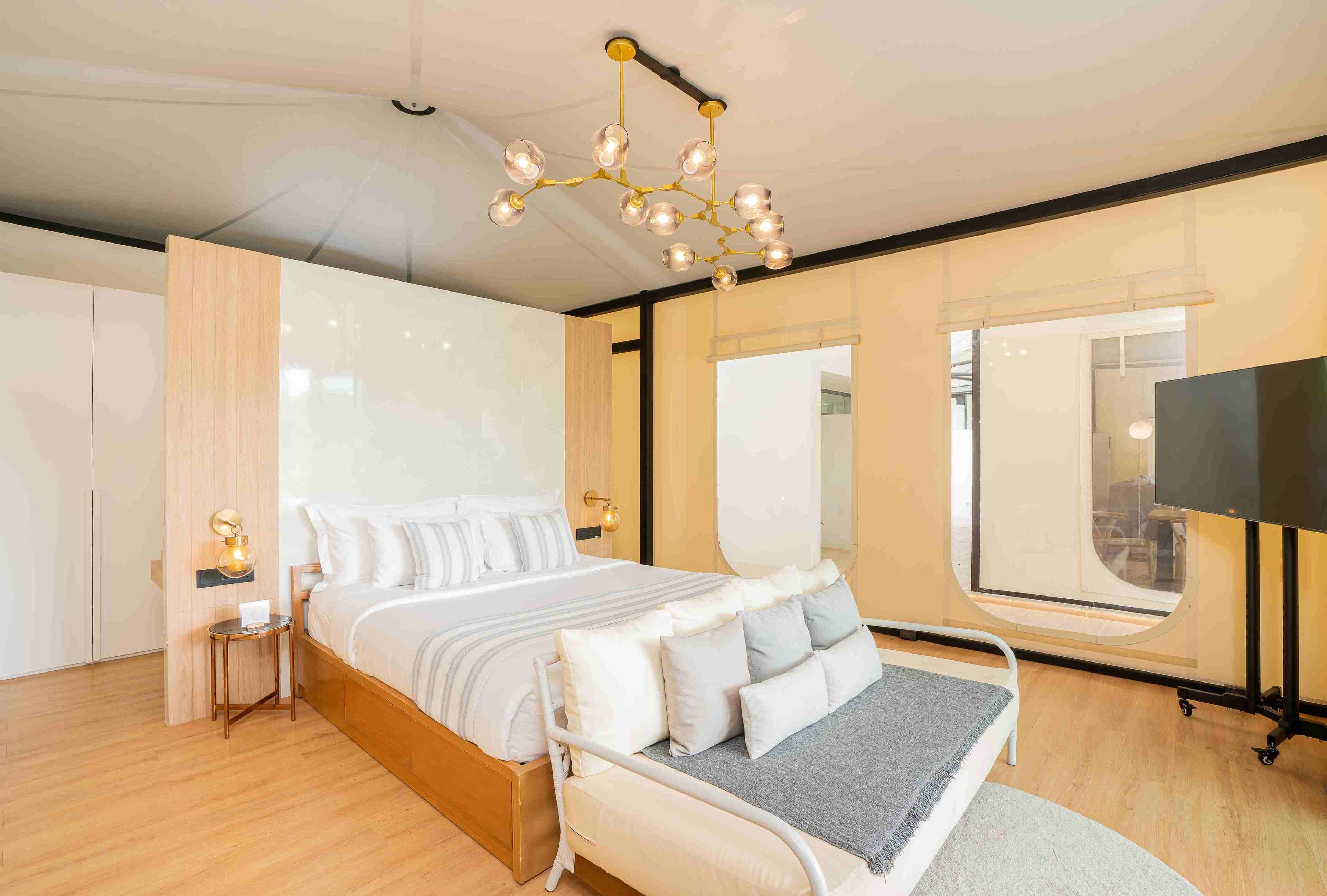 Una camera da letto moderna con un letto grande, comodini, una TV e un lampadario originale.