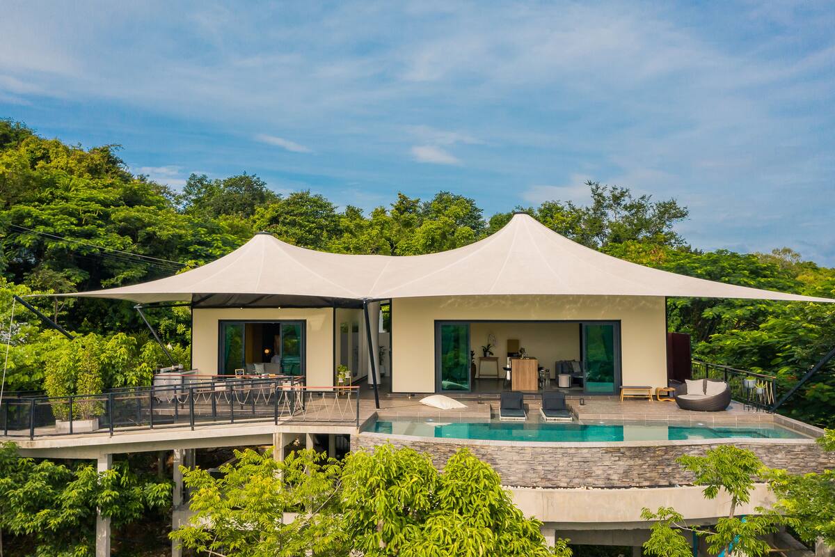 Una villa moderna con piscina, mobiliario exterior y terraza cubierta.