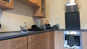 A modern kitchen with wooden cabinets, a stainless steel range hood, and an oven. - Great location 1 Bedroom Scotstoun Flat (Glasgow)