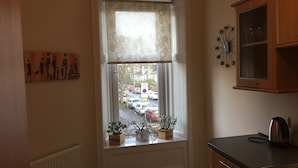 A kitchen with a window, wooden cabinets, a kettle, and a clock on the wall. - Great location 1 Bedroom Scotstoun Flat (Glasgow)