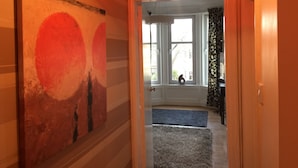 A hallway with a large abstract painting, a window with a view of the outside, and a door leading to another room. - Great location 1 Bedroom Scotstoun Flat (Glasgow)