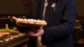A person in a dark suit holding a tray with small pastries.