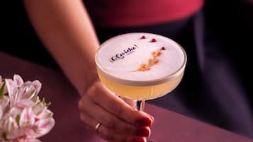 A person holding a cocktail glass with a frothy top and a label that reads "Côte d'Or."
