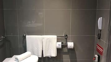 Een moderne badkamer met een toilet, twee handdoeken, een wc-papierhouder en een handdroger.