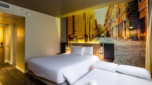 Quarto de hotel com uma cama grande, cabeceira com uma bicicleta e um mural de uma rua de paralelepípedos.