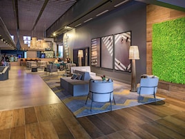 Un vestíbulo moderno con zonas de estar, un bar y una pared verde.