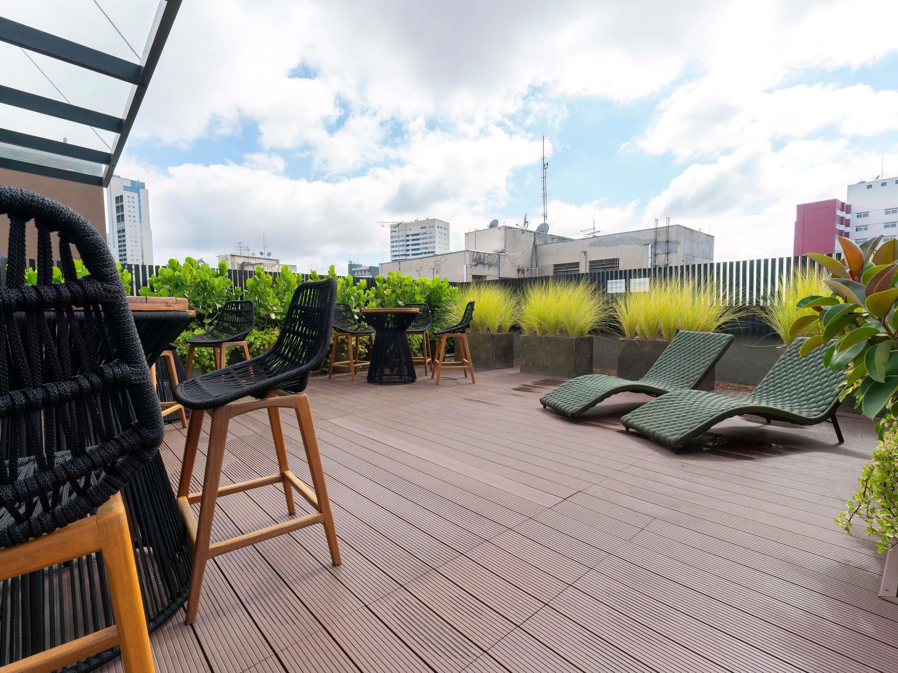 Una terraza en la azotea con sillones, una mesa y plantas en macetas.