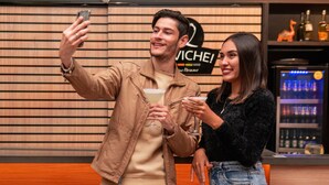 A man and a woman taking a selfie in a bar area with a 'MICHELE!' sign and a refrigerator stocked with beverages. - Novotel Curitiba Batel (Curitiba)