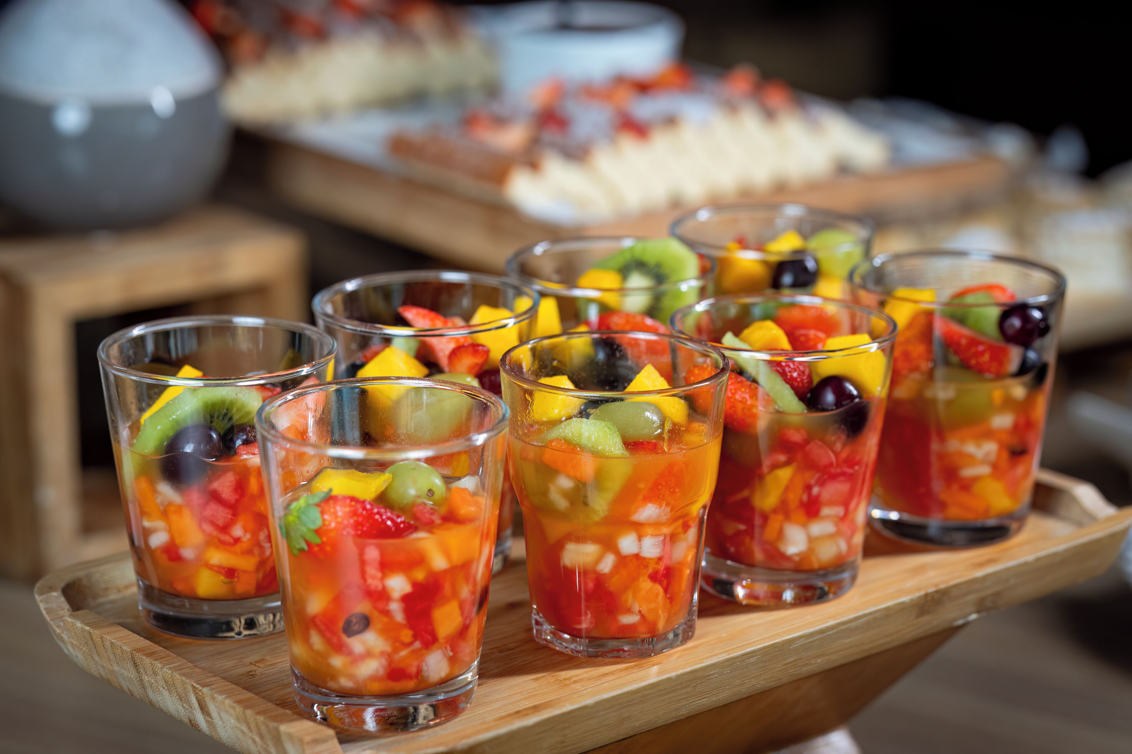 A tray of fruit cocktails on a wooden table.
