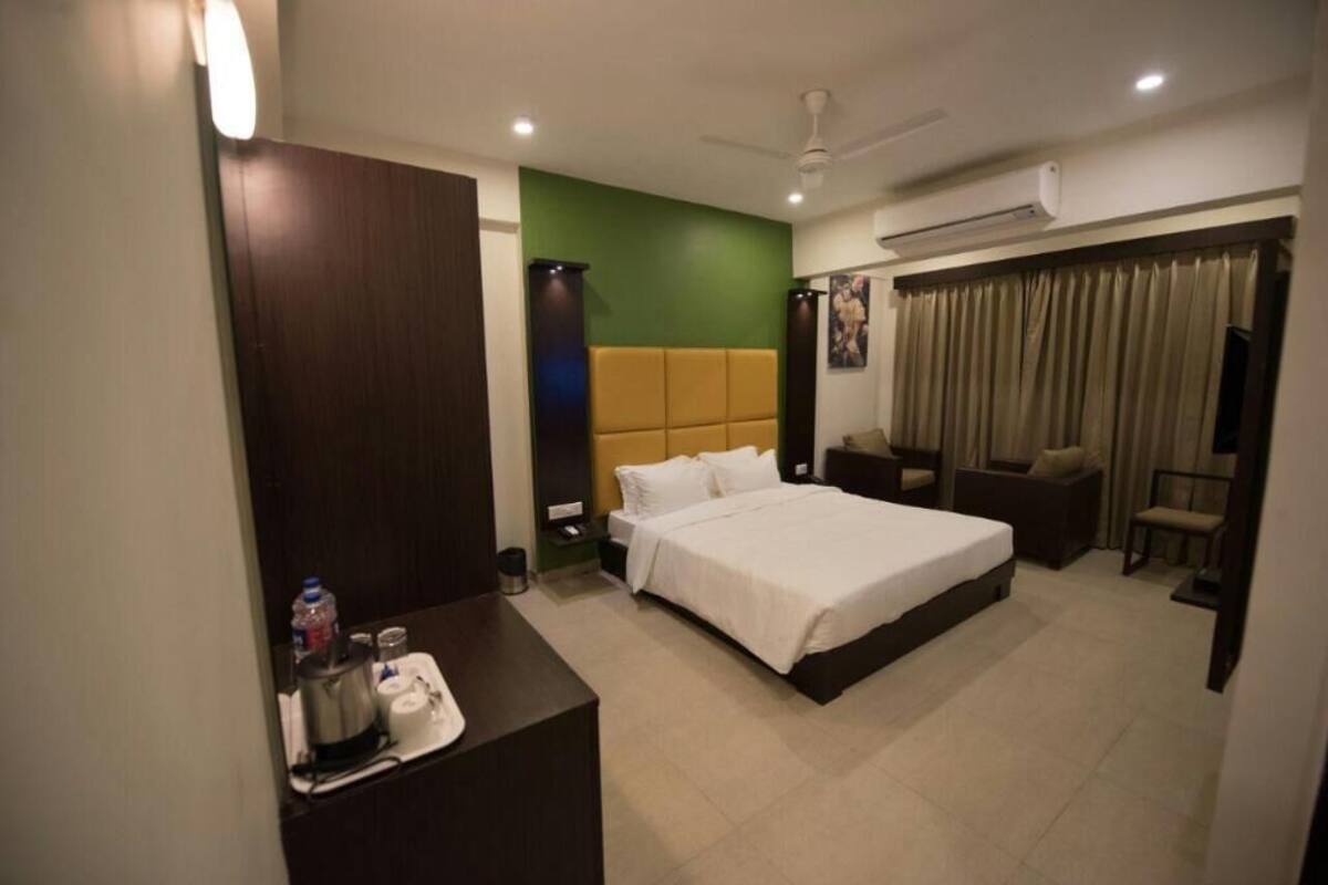 A hotel room with a bed, bedside table, chair, and a desk with a chair.