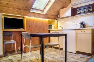 Una cocina compacta con armarios de madera, una mesa de comedor con dos sillas, un horno integrado y un microondas.
