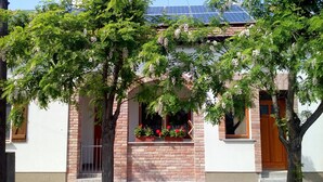 A building with a brick facade, a wooden door, and a window with a wooden frame. - Oázis Apartmanok (Morahalom)