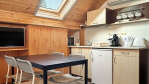 A compact kitchen with wooden cabinets, a built-in microwave, a coffee machine, and a dishwasher. - Oázis Apartmanok (Morahalom)