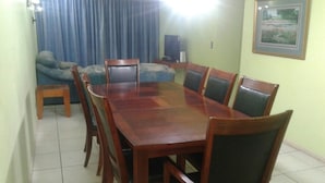Un comedor con una mesa y sillas de madera, un sofá, una mesita auxiliar y un televisor.