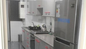 Una cocina moderna con electrodomésticos de acero inoxidable, gabinetes grises y suelo de baldosas.