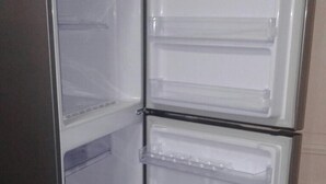 Un refrigerador con varios estantes transparentes y un compartimento congelador.