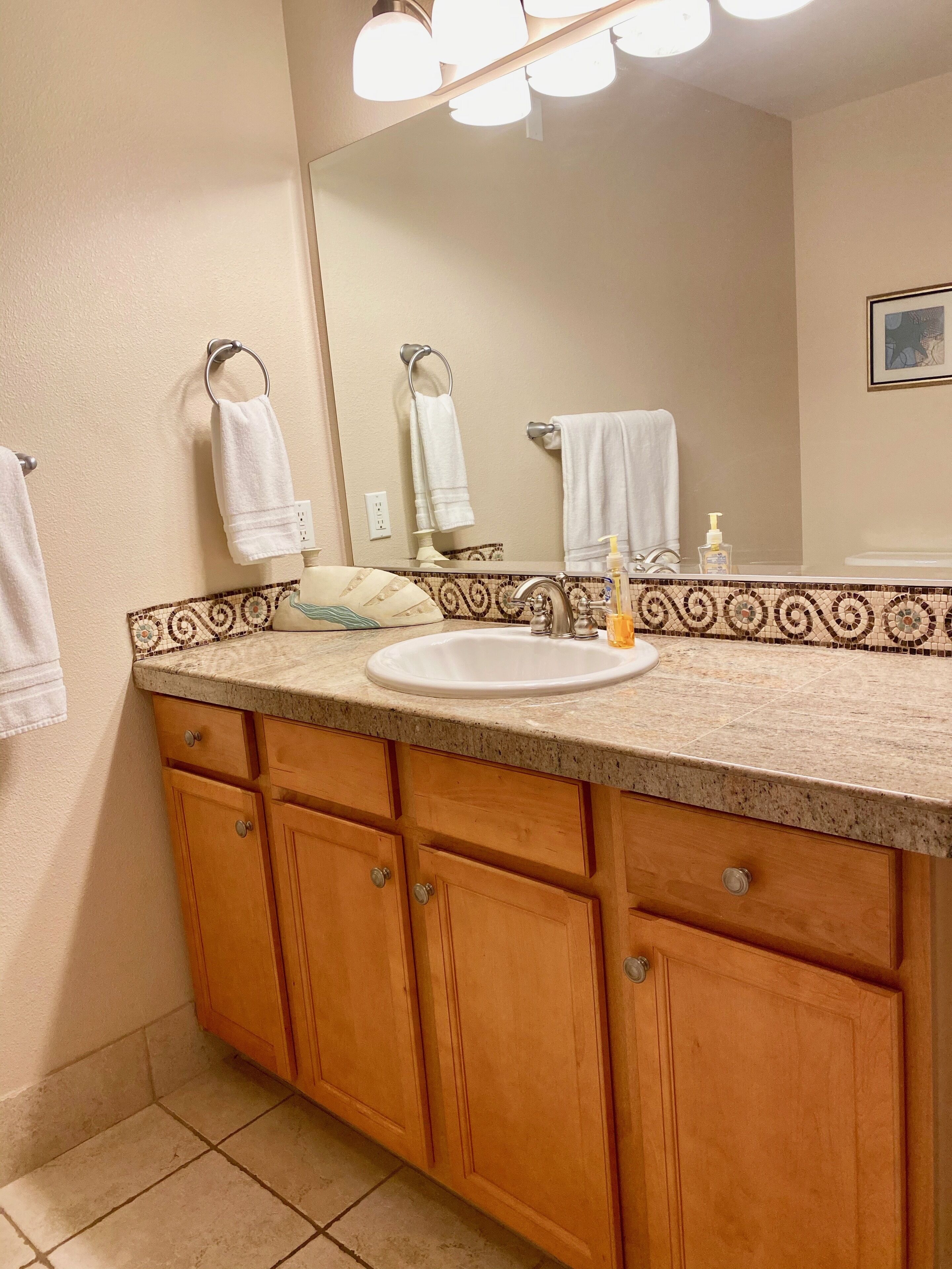 A bathroom with a sink, mirror, and wooden cabinets.