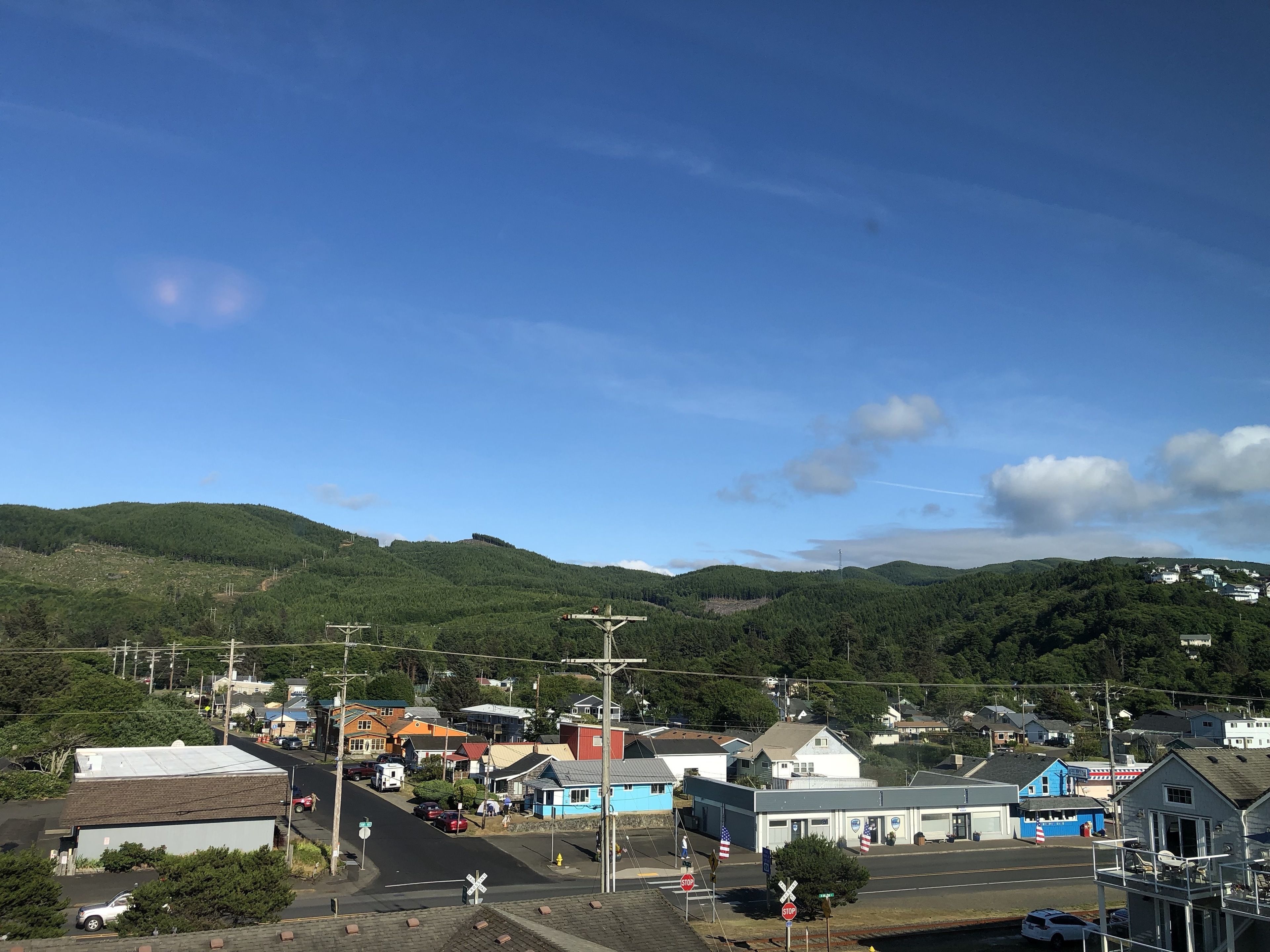 A small town with a railroad crossing, houses, and a hill in the background.