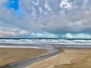 A beach with a sandy shore and waves crashing onto the beach.