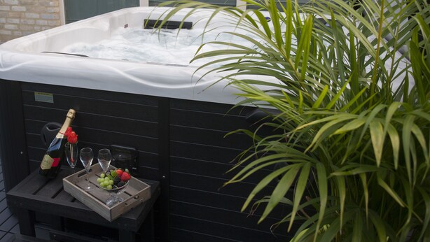 A hot tub with a bottle of champagne, glasses, and a tray with fruit. - B&B De Watering (Lommel)