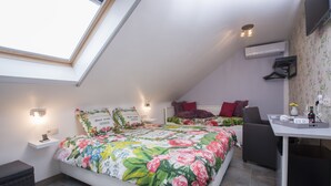 A bedroom with a skylight, a bed with floral bedding, a bedside table with a lamp, and a small desk with a chair. - B&B De Watering (Lommel)
