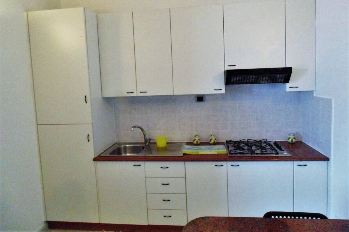 A small kitchen with white cabinets, a sink, a stove, and a countertop.