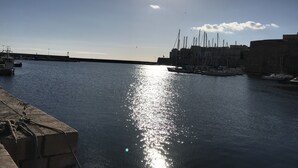 A marina with boats docked, a clear sky, and a sun reflecting on the water. - Residence Massilor (Gallipoli)
