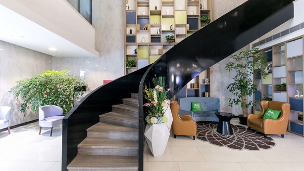 A modern interior with a black spiral staircase, a seating area with sofas and a coffee table, and a large bookshelf. - Ibis Styles Shanghai Hongqiao Airport (Shanghai)