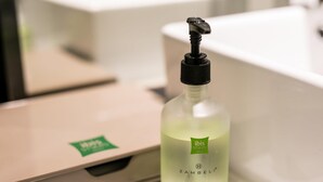 A bottle of liquid soap with a pump dispenser, placed on a countertop next to a beige suitcase. - Ibis Styles Shanghai Hongqiao Airport (Shanghai)