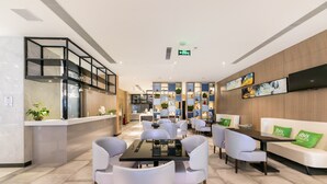 A modern hotel lobby with a reception desk, seating area, and a TV mounted on the wall. - Ibis Styles Shanghai Hongqiao Airport (Shanghai)