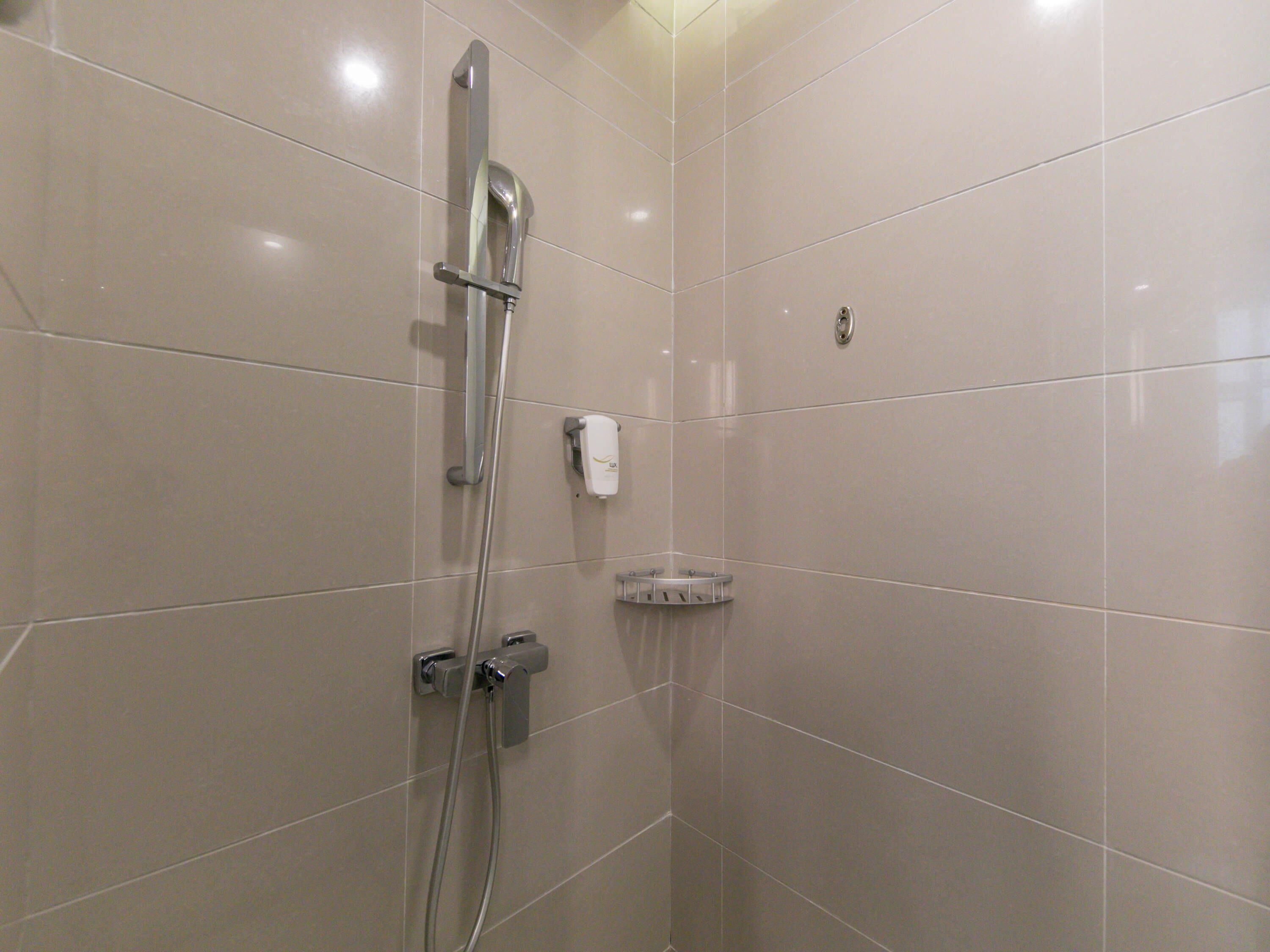 Un baño moderno con ducha, dispensador de jabón y secador de manos.