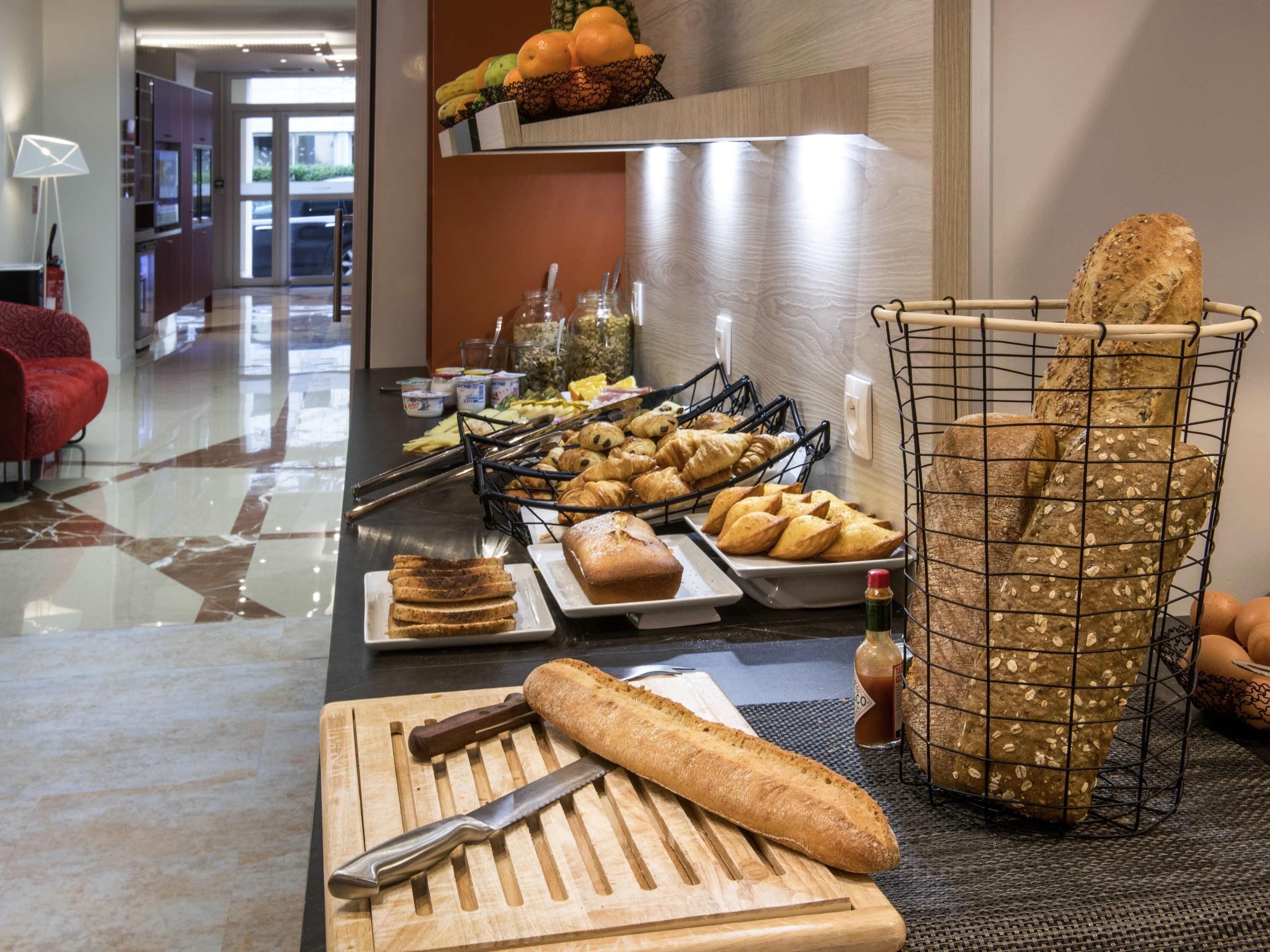 A breakfast buffet with bread, pastries, and fruits.