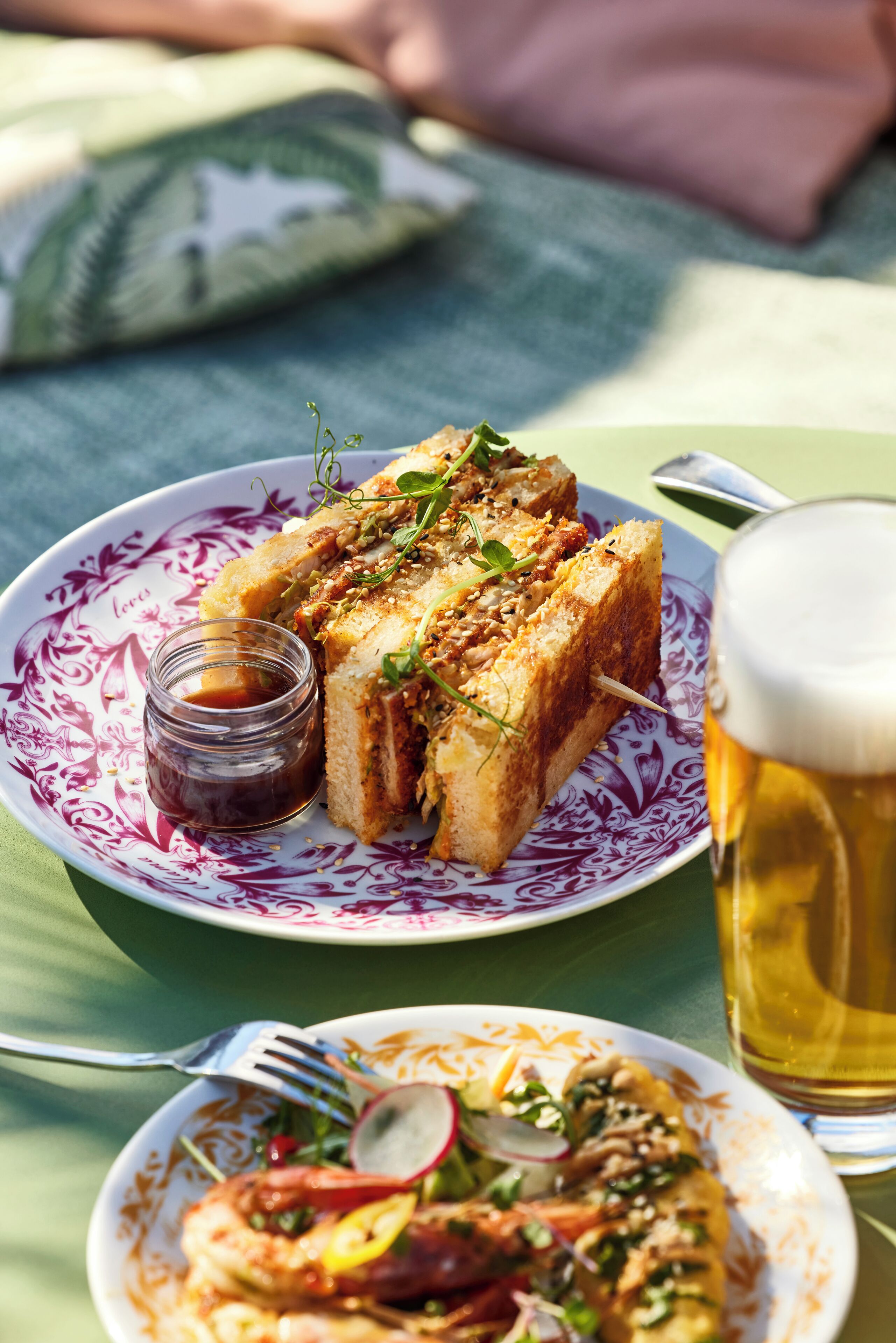 A meal with a sandwich and a glass of beer on a table.